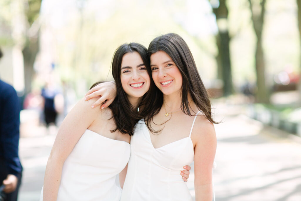 two young women in white celebrating their graduation from college